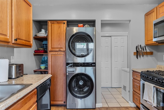 kitchen with stacked washing machine and dryer, appliances with stainless steel finishes, open shelves, light tile patterned flooring, and brown cabinetry