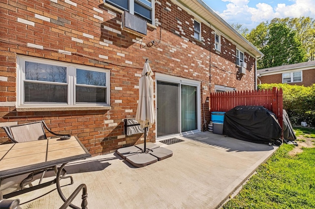 rear view of house featuring brick siding, fence, and a patio