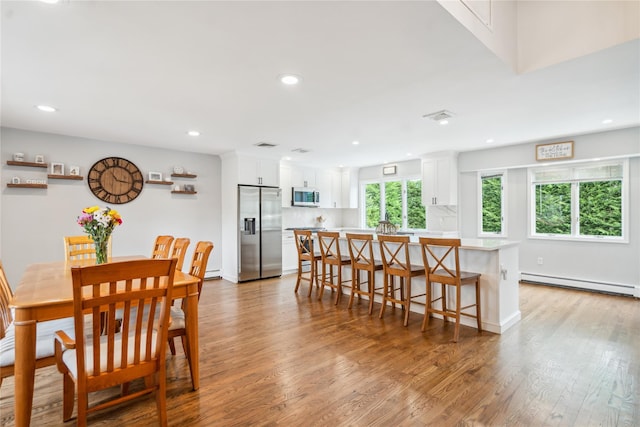 dining space featuring a baseboard heating unit, light wood-style flooring, recessed lighting, and baseboards