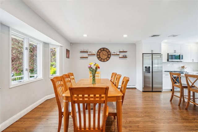 dining room featuring a baseboard heating unit, recessed lighting, light wood finished floors, and baseboards