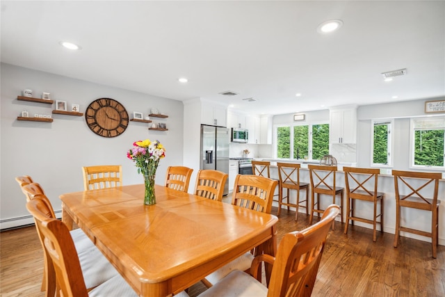dining room with wood finished floors, recessed lighting, and a baseboard heating unit