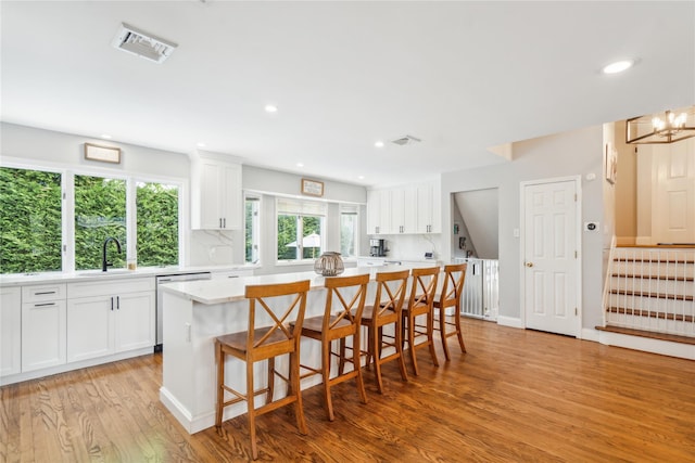 kitchen featuring a center island, white cabinetry, light wood-style flooring, decorative backsplash, and recessed lighting