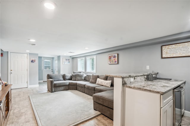 living room with baseboards, light wood finished floors, and recessed lighting