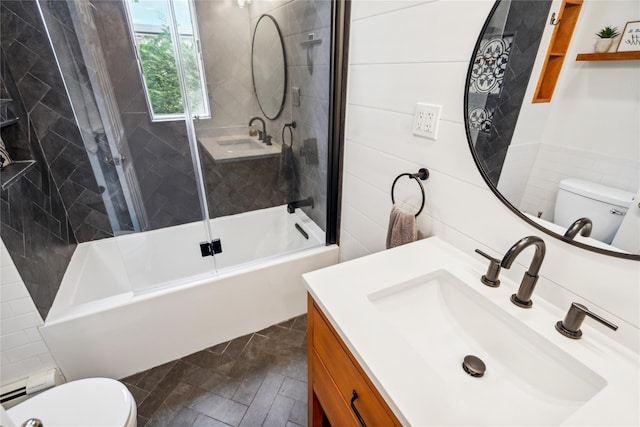 bathroom with toilet, combined bath / shower with glass door, vanity, and tile walls