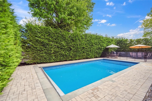 view of swimming pool featuring a patio area, outdoor dining area, and fence