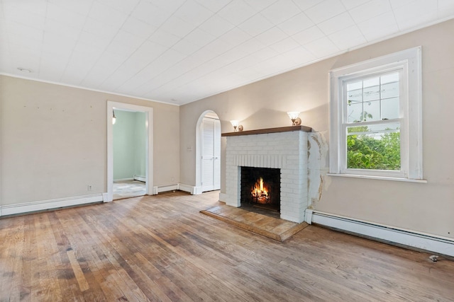 803 Oakwood Dr, Peekskill, NY 10566 - unfurnished living room with a brick fireplace, wood-type flooring, a baseboard heating unit, arched walkways, and ornamental molding
