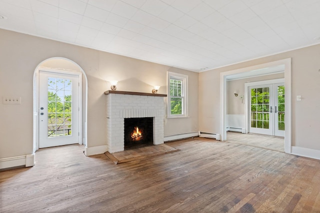 803 Oakwood Dr, Peekskill, NY 10566 - unfurnished living room featuring wood finished floors, a fireplace, baseboard heating, and french doors