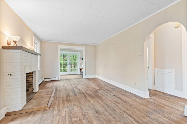 803 Oakwood Dr, Peekskill, NY 10566 - unfurnished living room featuring arched walkways, crown molding, hardwood / wood-style floors, a brick fireplace, and baseboard heating