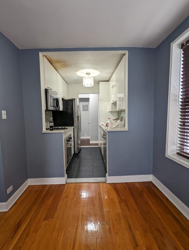 kitchen featuring appliances with stainless steel finishes, dark wood-style flooring, light countertops, and baseboards