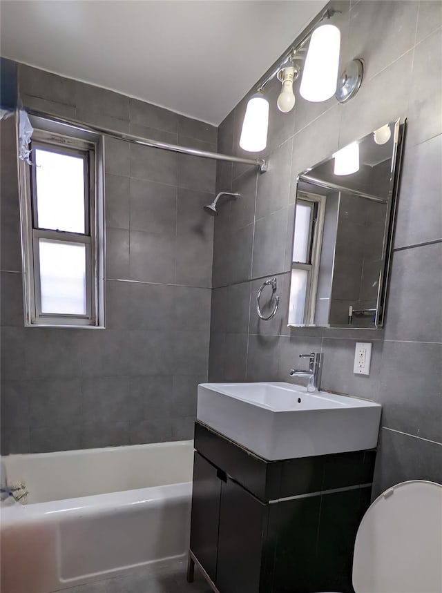 full bath with tile walls, shower / bath combination, toilet, and vanity