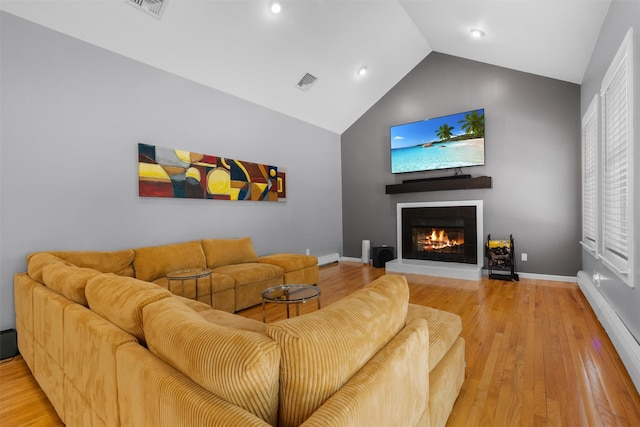 9 Hill Rd, Washingtonville, NY 10992 - living area featuring a baseboard heating unit, a warm lit fireplace, vaulted ceiling, light wood-style floors, and baseboards