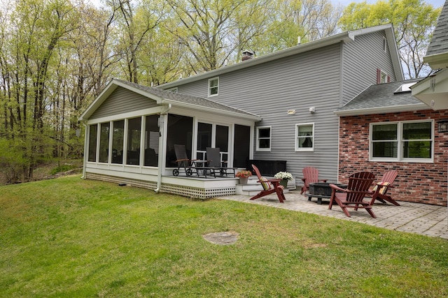 rear view of house featuring a sunroom, a patio area, a chimney, and a shingled roof
