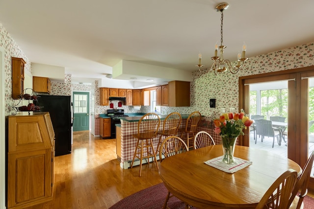 dining area featuring wallpapered walls, light wood-style flooring, and a chandelier
