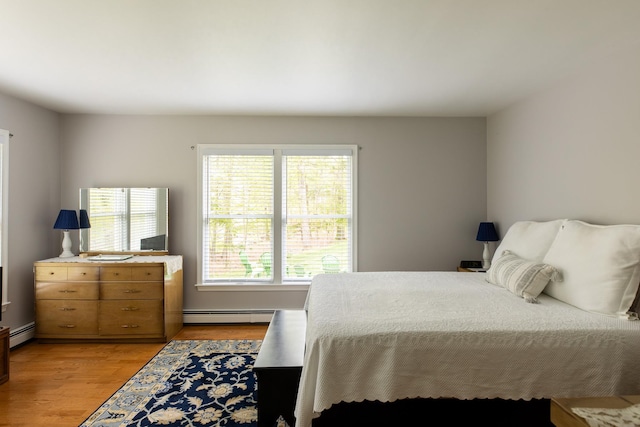 bedroom with baseboard heating and light wood finished floors
