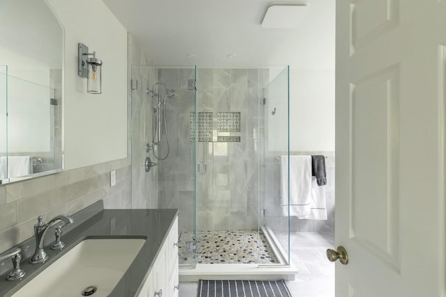 full bathroom with a shower stall, vanity, tile walls, and tasteful backsplash