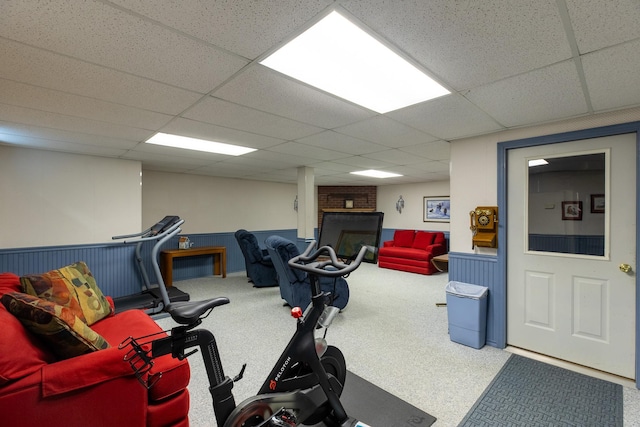 workout area with a drop ceiling and a wainscoted wall