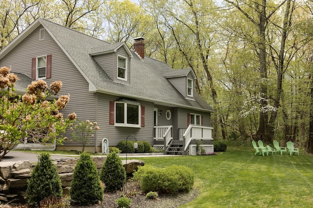 view of front of house with a shingled roof, a chimney, and a front lawn
