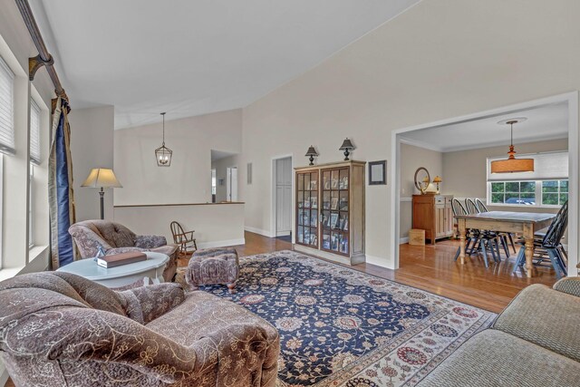 living area with wood finished floors, lofted ceiling, and baseboards