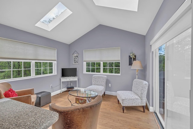 living area with a skylight, plenty of natural light, lofted ceiling, and light wood-style flooring