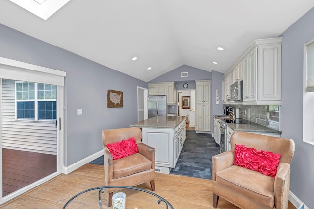 living area with lofted ceiling, wood finished floors, baseboards, a skylight, and recessed lighting