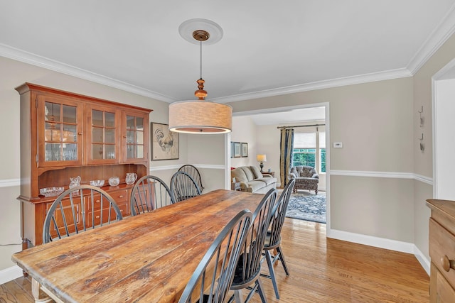 dining area featuring light wood-style floors, baseboards, and crown molding