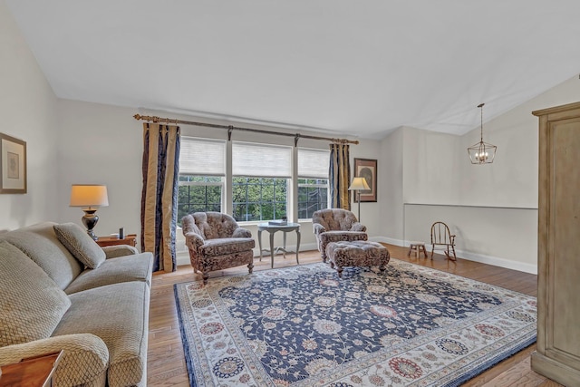 living area featuring light wood-style floors, vaulted ceiling, and a chandelier