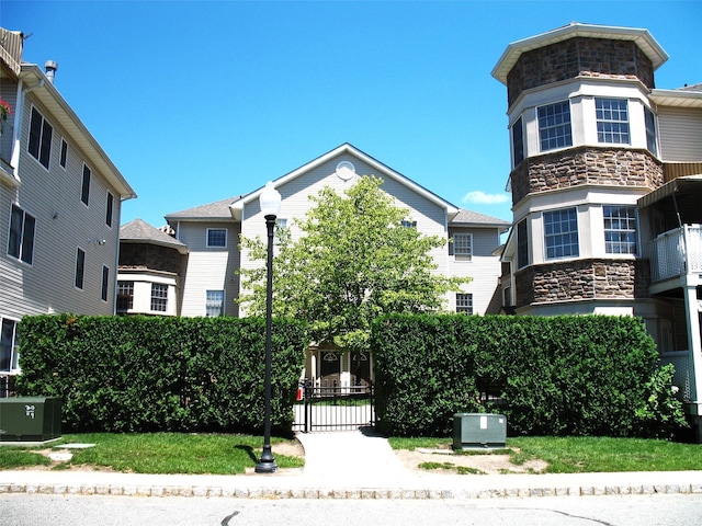 view of front of home with stone siding and a gate
