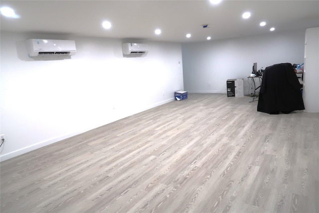 finished basement with a wall unit AC, recessed lighting, light wood-type flooring, and baseboards