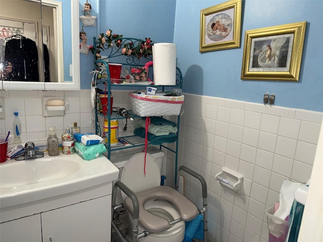 bathroom featuring tile walls, vanity, toilet, and a wainscoted wall