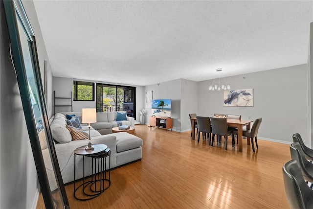 25 Rockledge Ave Unit 501, White Plains, NY 10601 - living room with a textured ceiling, a chandelier, light wood-style flooring, and baseboards
