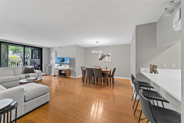 25 Rockledge Ave Unit 501, White Plains, NY 10601 - living area featuring a textured ceiling, a chandelier, light wood finished floors, and baseboards