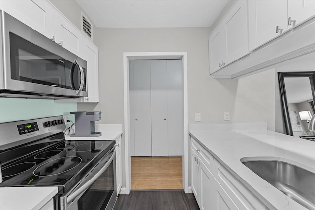 25 Rockledge Ave Unit 501, White Plains, NY 10601 - kitchen featuring appliances with stainless steel finishes, dark wood-type flooring, and white cabinets