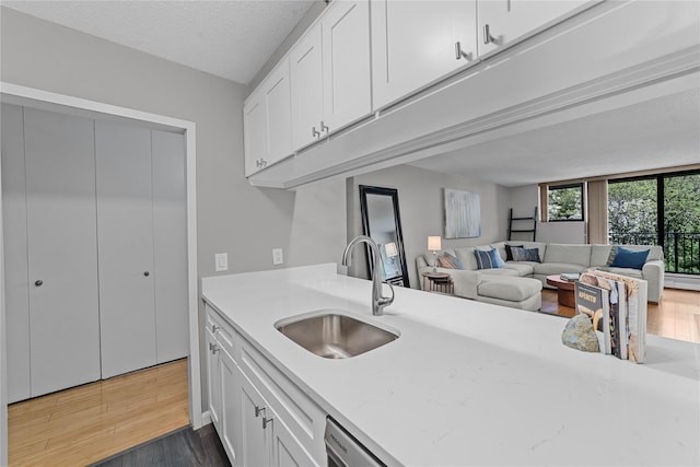 25 Rockledge Ave Unit 501, White Plains, NY 10601 - kitchen featuring a sink, light wood-style floors, white cabinets, open floor plan, and light stone countertops