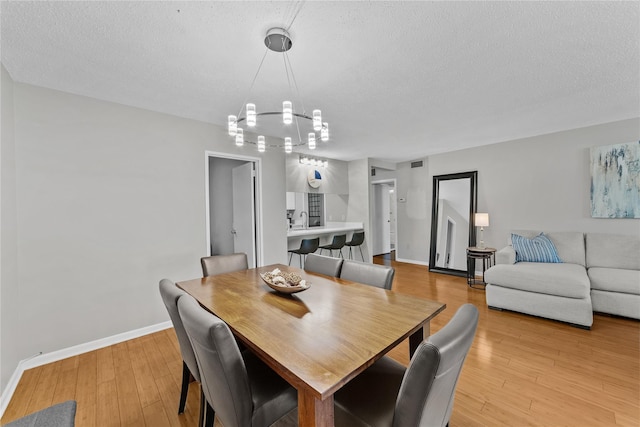 25 Rockledge Ave Unit 501, White Plains, NY 10601 - dining room with baseboards, a textured ceiling, light wood-style floors, and a chandelier