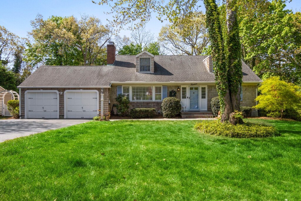 14 Caleb Brewster Rd, East Setauket, NY 11733 - cape cod house featuring an attached garage, concrete driveway, a front yard, and roof with shingles