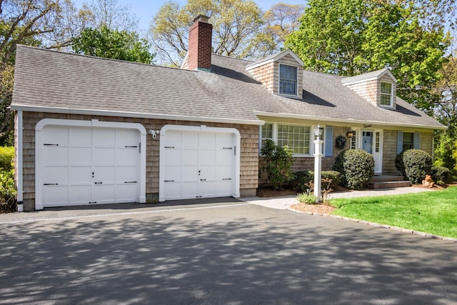 cape cod house with roof with shingles, an attached garage, and a chimney