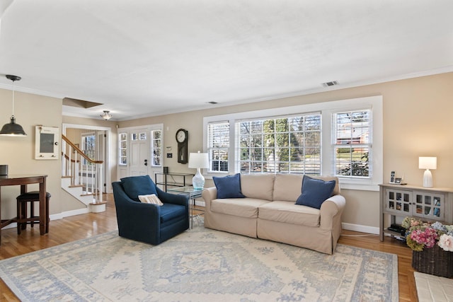 living room with baseboards, stairs, ornamental molding, and wood finished floors