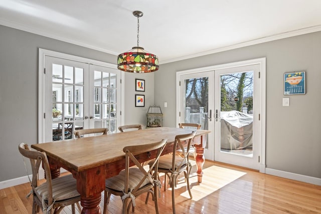 dining area featuring french doors, baseboards, crown molding, and light wood-style flooring