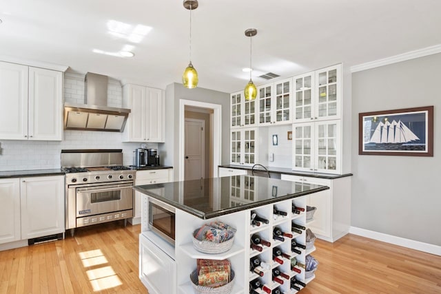 kitchen with wall chimney exhaust hood, open shelves, appliances with stainless steel finishes, white cabinets, and light wood-type flooring
