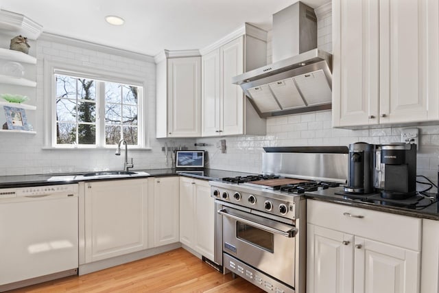 kitchen featuring white dishwasher, stainless steel range, wall chimney range hood, light wood-type flooring, and backsplash