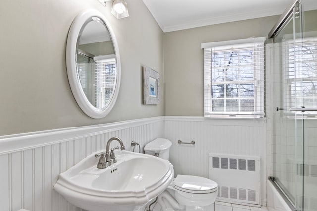 full bathroom featuring radiator heating unit, a sink, toilet, a wainscoted wall, and ornamental molding