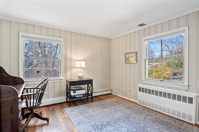 office featuring radiator, healthy amount of natural light, ornamental molding, hardwood / wood-style flooring, and baseboards
