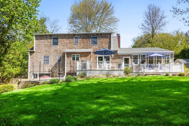 rear view of house with a deck, a yard, and a chimney