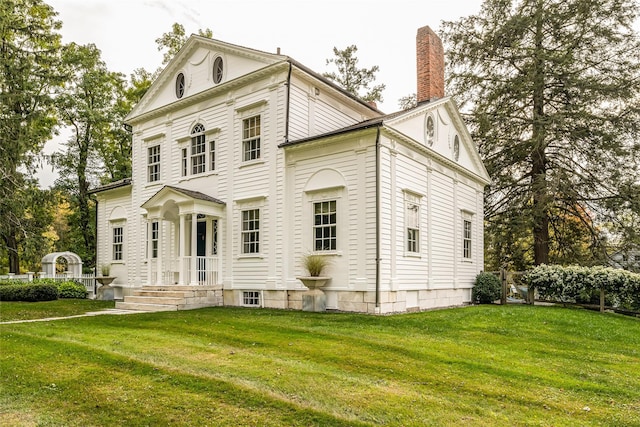 rear view of house with a chimney and a lawn