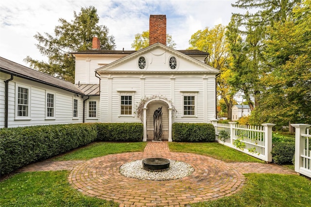 neoclassical / greek revival house featuring a chimney