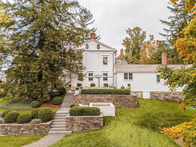 back of house featuring a yard, a chimney, and stairway