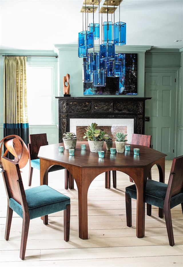 dining area with a premium fireplace, crown molding, and wood finished floors