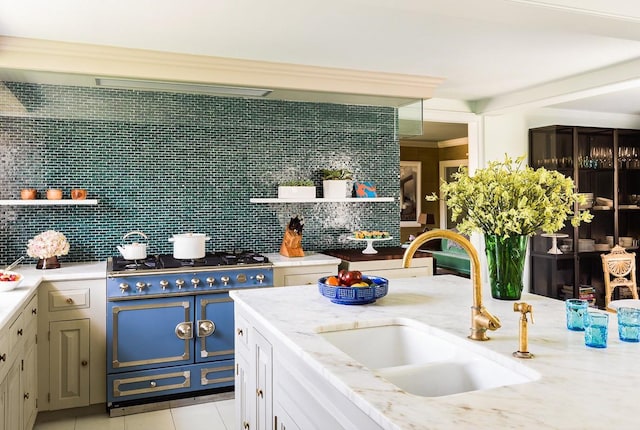 kitchen featuring double oven range, a sink, light tile patterned flooring, and backsplash
