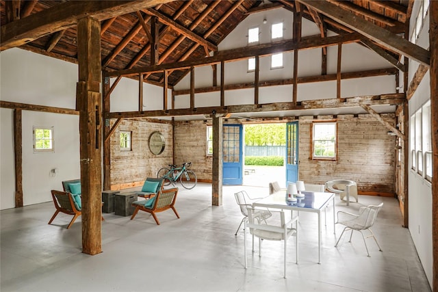 dining space with plenty of natural light, high vaulted ceiling, and concrete flooring