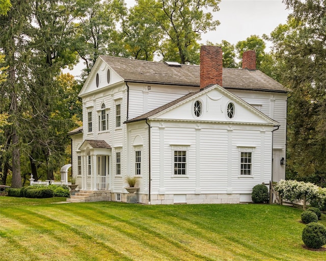 rear view of property featuring a chimney and a yard